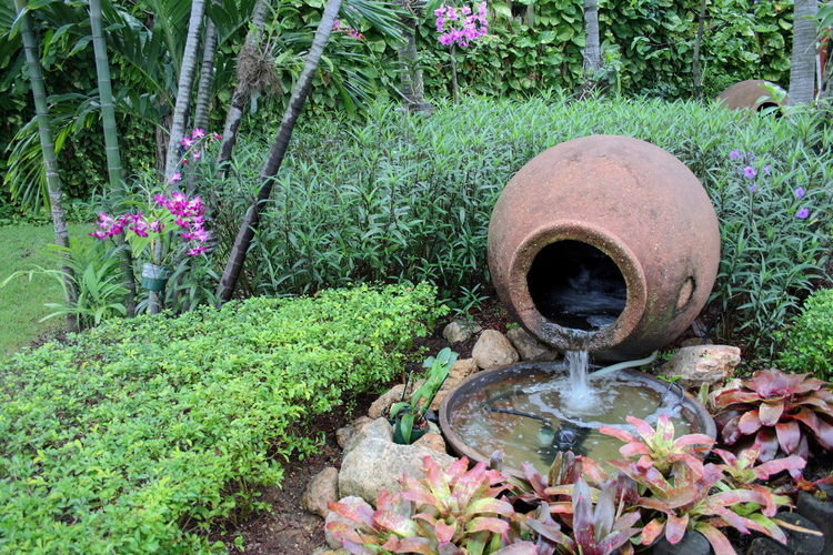 fontana u obliku krčaga smeštena među bujnim zelenilom u bašti